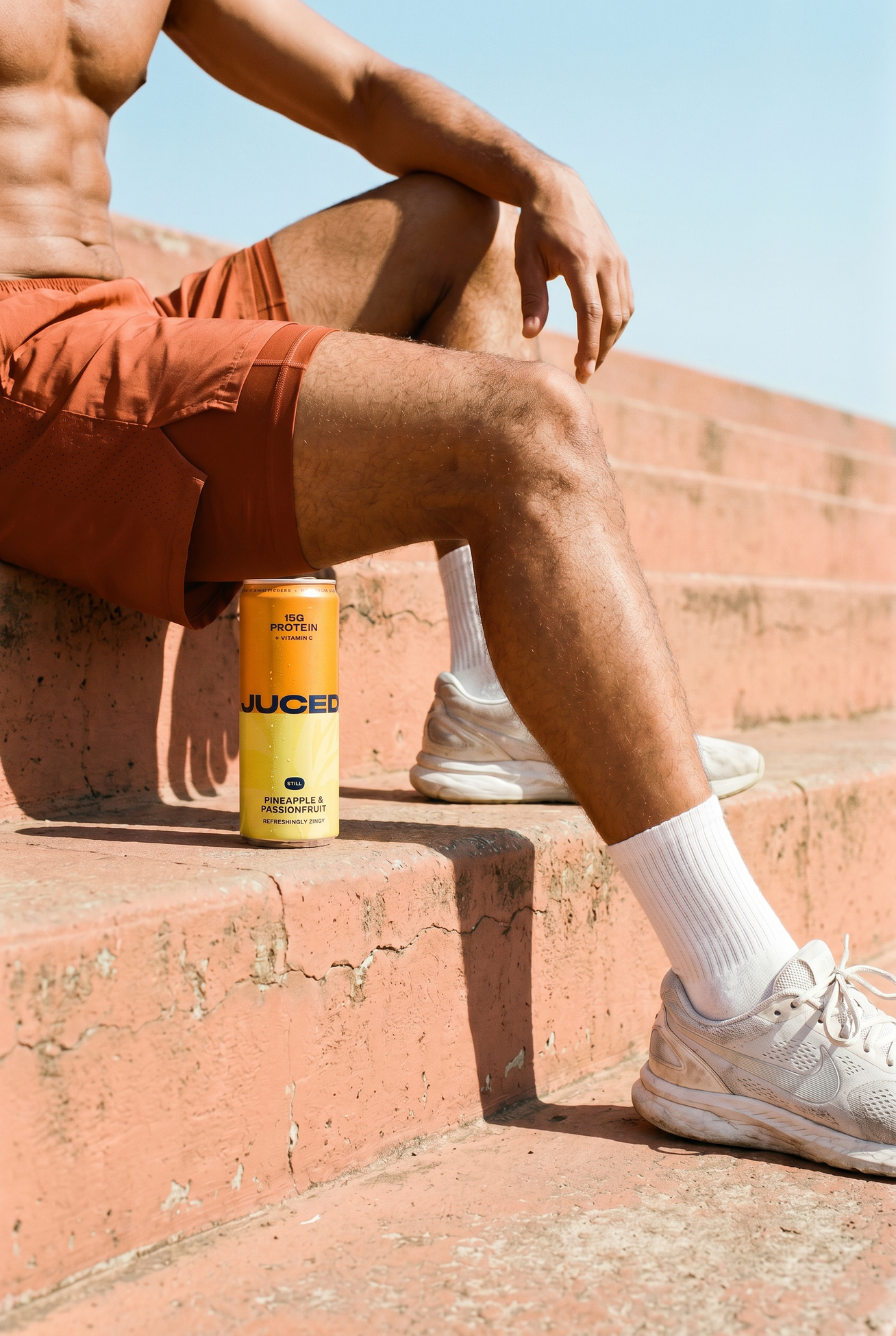 Person sat on steps with a cold can of JUCED high collagen fruit drink.