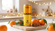A can of JUCED Orange, Peach & Ginger on a festive kitchen counter surrounded by clementines, cinnamon sticks and winter greenery