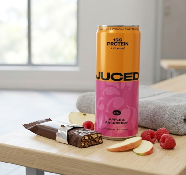A can of JUCED protein drink next to a protein bar on a gym bench, comparing the two snack formats
