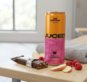A can of JUCED protein drink next to a protein bar on a gym bench, comparing the two snack formats