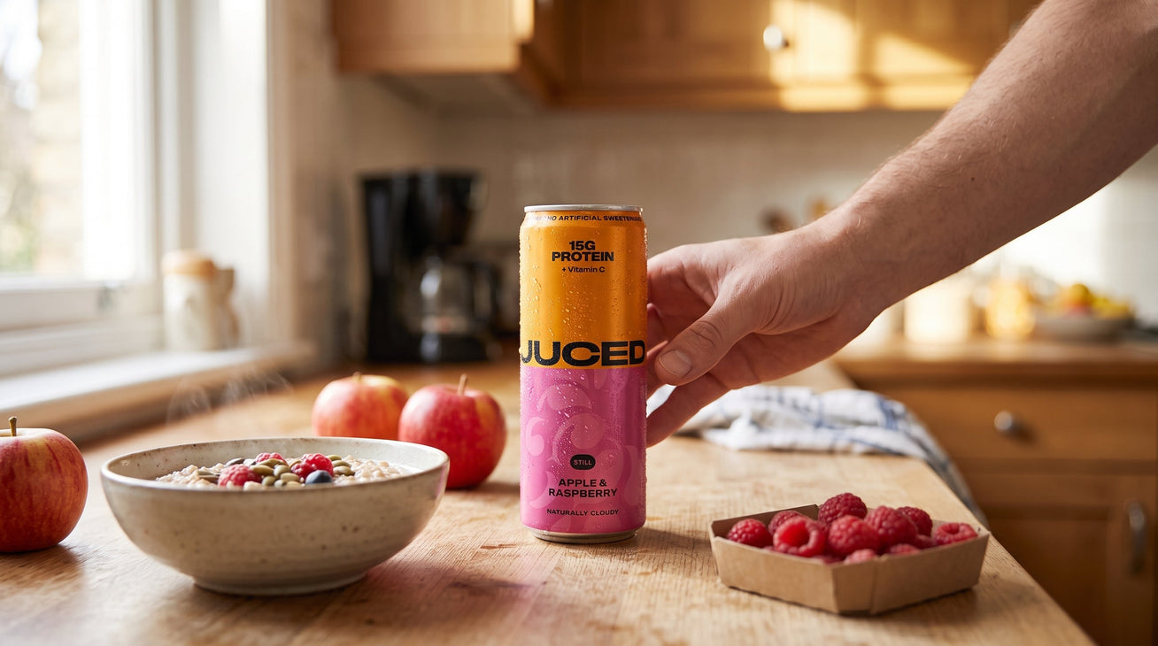 Family kitchen scene with a can of JUCED Cloudy Apple and Raspberry protein drink alongside breakfast, representing a clean protein drink for families