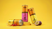 three cans of JUCED next to each other on a yellow background surrounded by fruits