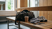Open gym bag, paper coffee cup and trainers on a changing room bench
