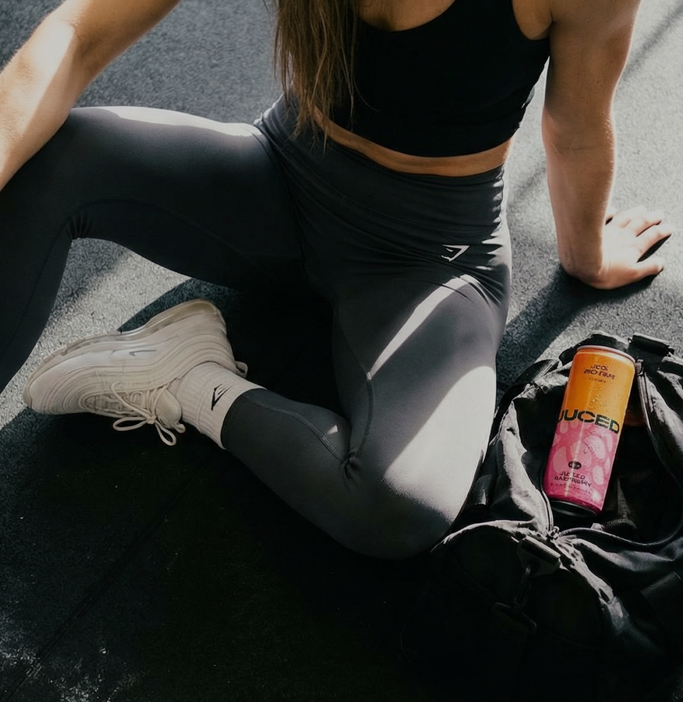 Person in athletic wear stretching on a road with a JUCED drink can nearby.