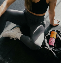 Person in athletic wear stretching on a road with a JUCED drink can nearby.